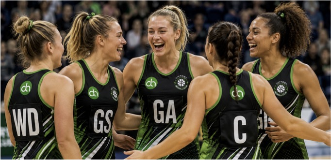 Netball players in netball dresses stood in a huddle